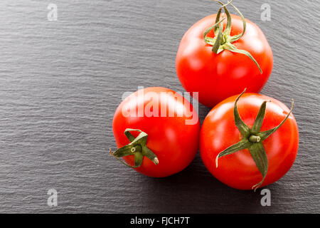Tomaten auf einem schwarzen Stein Hintergrund. Stockfoto