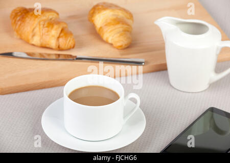 Tasse Milchkaffee mit frischen goldenen Croissants auf dem Tisch zum Frühstück Stockfoto