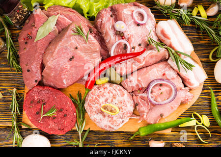 Schneidebrett mit große Stücke Fleisch mit Kräutern und Paprika kochbereit bedeckt überfüllt Stockfoto