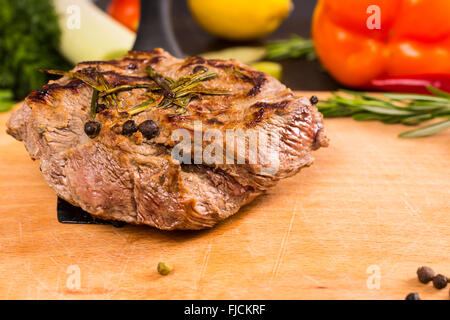 Stillleben mit Platte aus erfahrenen Roastbeef ruht auf Holzbrett mit frischen Kräutern und Gemüse und textfreiraum hautnah. Stockfoto