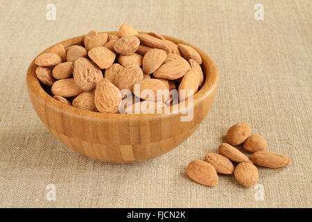 Gesalzene Mandeln in Bambusschüssel auf groben Leinentuch groß geschält Stockfoto