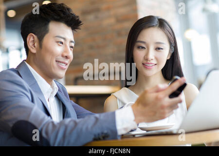Chinesischer Unternehmer und Unternehmerin Blick auf Smartphone im café Stockfoto