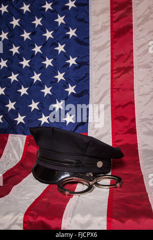 Eine Polizeimütze mit Handschellen an eine amerikanische Flagge Hintergrund. Stockfoto