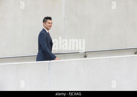 Seitenansicht eines glücklich asiatischen Geschäftsmann zu Fuß auf der Stadtstraße. Stockfoto