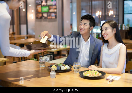 Junge Chinesen Mann bezahlte Rechnung per Kreditkarte im restaurant Stockfoto