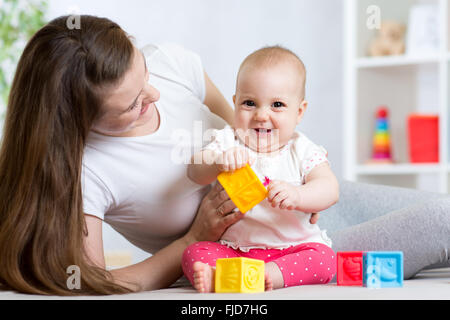 Mutter und Baby Mädchen spielen mit Farbe Entwicklungsstörungen Spielsachen im Kinderzimmer Stockfoto