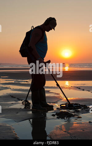 Metal Detecting bei Sonnenaufgang am Strand von Bournemouth Stockfoto