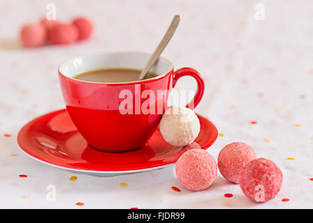 Rote Kaffeetasse mit Süßigkeiten auf Tisch Stockfoto