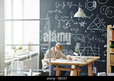 Junger Mann am Schreibtisch und seine Hausaufgaben Stockfoto