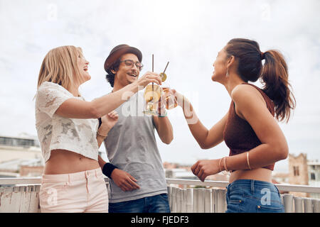 Im Freien Schuss junger Menschen auf einer Party Cocktails genießen. Drei junge Freunde Toasten Getränke während Party auf dem Dach. Stockfoto