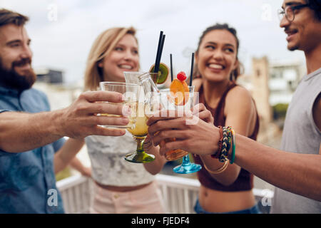 Freunde, Spaß und tranken Cocktails im Freien auf einem Dach zusammenkommen. Gruppe von Freunden rumhängen und Toasten trinkt ou Stockfoto