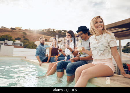 Multi-ethnischen Gruppe von jungen Leuten hängen von Schwimmbad mit Cocktails. Glückliche Freunde Party am Pool genießen. Stockfoto