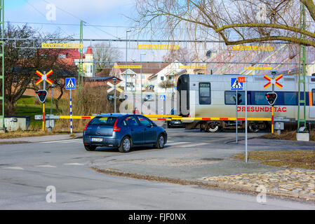 Solvesborg, Schweden - 27. Februar 2016: Autos werden an einem Bahnübergang angehalten, während der Zug vorbei. Rote Leuchten blinken Stockfoto