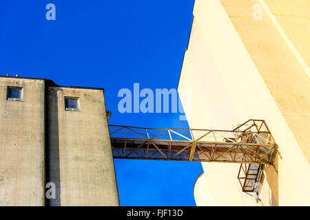 Einen erhöhten Laufsteg in der Luft zwischen zwei alte und verlassene Industriebauten. Blauen Himmel im Hintergrund. Kopieren Sie Raum. Stockfoto