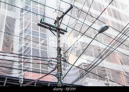 Stromleitungen auf elektrische Pol vor einem Gebäude im Bau Stockfoto