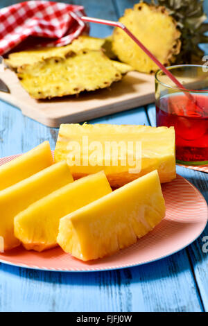 Nahaufnahme einer Platte mit frisch Ananas schneiden auf einem blauen rustikalen Holztisch Stockfoto