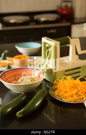 Eine Sprializer dient Spralize Zucchini (oder Zucchini) neben Sprialised-Butternut-Kürbis in einer Landhausküche Stockfoto