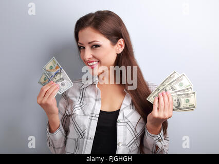 Erfolgreiche junge hübsche Frau mit US-Dollar in zwei Händen mit toothy Lächeln auf den Lippen. Stockfoto