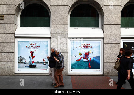 Ältere Frauen vorbeigehen Werbung für Baskepensiones Pensionspläne auf Kutxabank Gebäude, Bilbao, Baskenland, Spanien Stockfoto