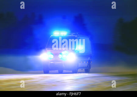 Krankenwagen auf Notruf mit Blaulicht in die blaue Nacht Stockfoto