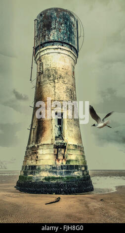 Alter Leuchtturm am Strand mit einer Möwe fliegen darauf Stockfoto