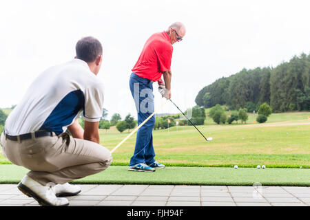 Golftrainer arbeiten mit Golfer auf der driving-range Stockfoto