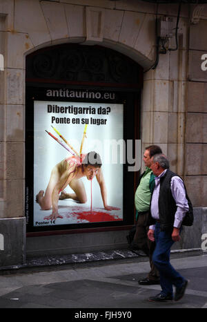 Menschen zu Fuß vorbei an einem Plakat im Fenster protestieren gegen Stierkampf, Casco Viejo, Bilbao, Baskenland, Spanien Stockfoto