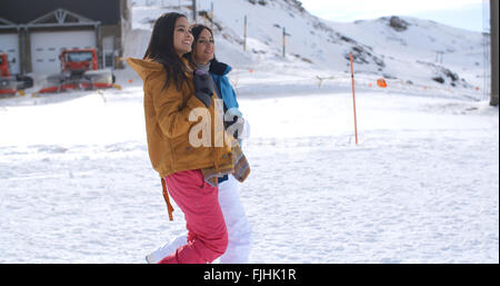 Zwei junge Frauen, die zu Fuß durch den Schnee in einem resort Stockfoto