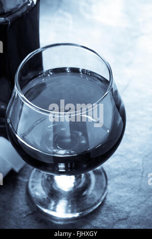 Cognac-Glas und Flasche auf Tisch Stockfoto
