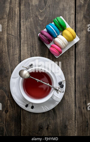 Bunte Makronen mit Tasse Tee auf hölzernen Hintergrund Stockfoto