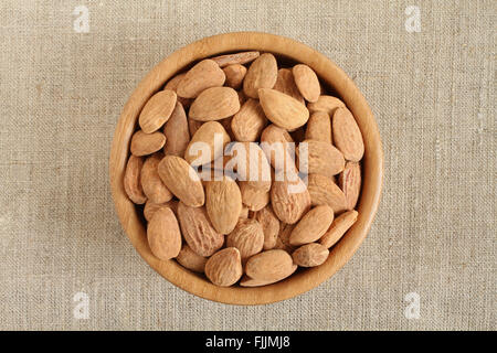 Gesalzene Mandeln in Bambusschüssel auf groben Leinentuch groß geschält Stockfoto