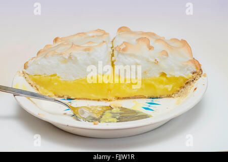 Hälfte der Zitronen-Baiser Sahne Torte, mit Portion Utensil. Ausschnitt. Stockfoto