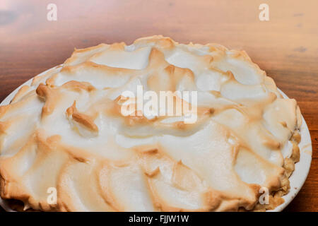 Nahaufnahme einer ganzen Zitronenmeringue-Pastete auf einem Holztisch. Stockfoto