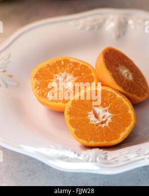 Drei Hälften des Mandarin-Orangen auf einem weißen Teller, Nahaufnahme. Stockfoto