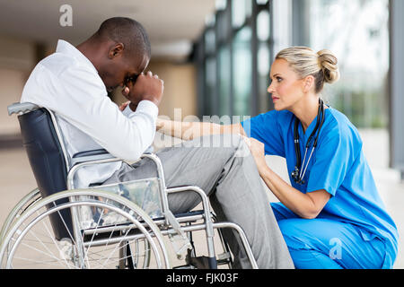 fürsorglich mittleren Alter Arzt beruhigend ein behinderten Patienten Stockfoto