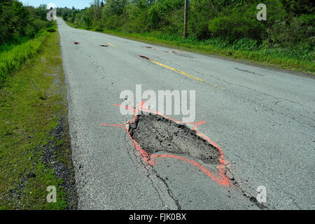 Ein großes Schlagloch auf eine asphaltierte Straße mit Farbe markiert. Stockfoto