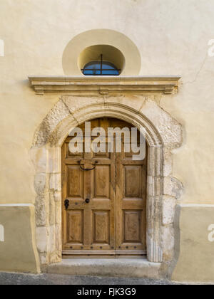 Schwere Holztür in einen alten steinernen Torbogen im historischen Dorf von Sablet, Vaucluse, Provence, Frankreich Stockfoto