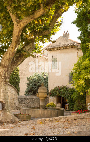 Ein Brunnen ist im Schatten einer alten Platane in der historischen mittelalterlichen Dorfplatz, Vaison-la-Romaine, Côtes du Rhône, Provence, Frankreich Stockfoto