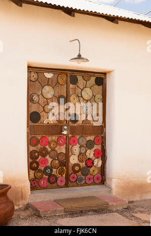 Türen mit rustikalen Holzmöbeln dekoriert mit alten Sägeblätter in Adobe Wall, Barrio Viejo, Tucson, Arizona. Einzigartige, kreative Wohnungen die lokale Architektur.
