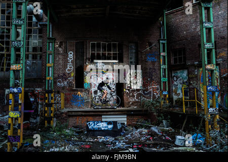 Auf einer Rolle mit Graffiti bemalt Radsportler, Trainer vor einer zerstörten Buling. Stockfoto