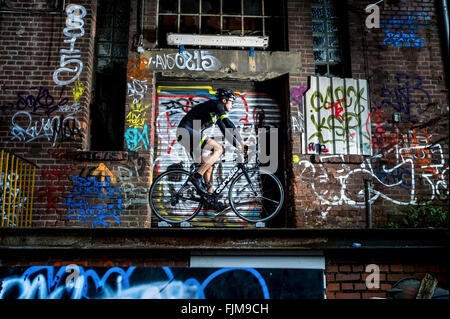 Auf einer Rolle mit Graffiti bemalt Radsportler, Trainer vor einer zerstörten Buling. Stockfoto