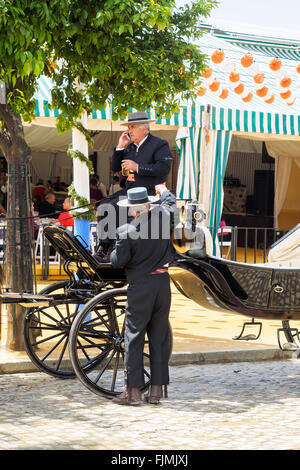 Sevilla, Spanien - 23. April 2015: Beförderung Treiber gekleidet in traditionellen "Traje Corto" mit Casetas hinter. Die Feria de Sevilla ' Feri Stockfoto