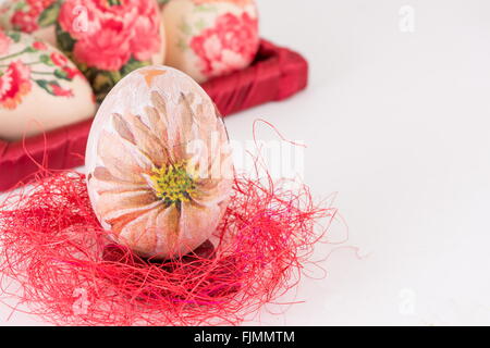 Serviettentechnik dekoriert Easter Egg auf roten Stroh Stockfoto