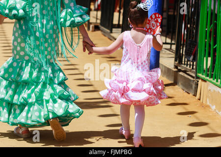 Sevilla, Spanien - 28. April 2015: Mutter und Tochter in traditioneller Kleidung zu Fuß neben Casetas auf der Messe Sevilla. Stockfoto
