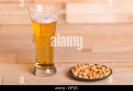 Kaltes Bier mit gerösteten Erdnüssen auf Holztisch, Still-Life-style Stockfoto