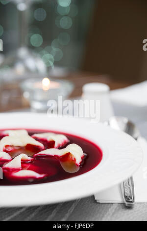 Traditionelle polnische rote Borschtsch-Suppe mit Knödeln auf weißen Teller. Sehr flach Dept Feld Stockfoto