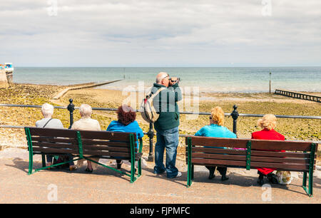 Touristen sitzen entspannt auf Llandudno Promenade genießen den Blick auf das Meer. Llandudno, North Wales, Großbritannien. Stockfoto