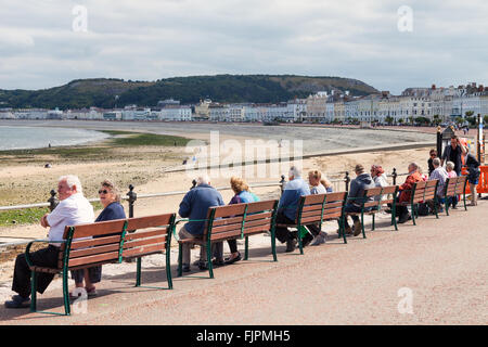 Touristen sitzen entspannt auf Llandudno Promenade genießen den Blick auf das Meer. Llandudno, North Wales, Großbritannien. Stockfoto