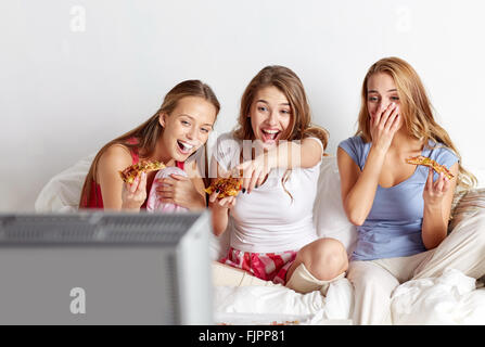 Glückliche Freunde Pizza essen und vor dem Fernseher zu Hause Stockfoto