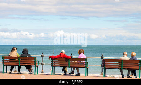 Touristen sitzen entspannt, Blick auf das Meer genießen Sie die Landschaft an warmen, windigen Tag in das Seebad Llandudno. Wales Stockfoto